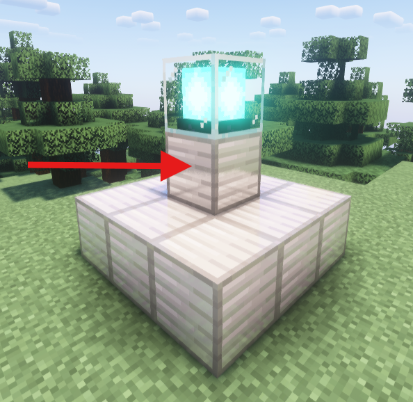 A Minecraft beacon placed on a 3x3 iron block base with an additional iron block under the beacon, highlighted by a red arrow pointing at the lower block.