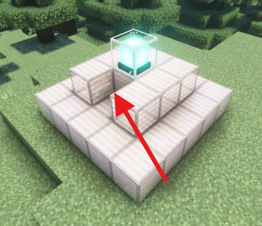 A Minecraft beacon placed on a stepped iron block pyramid, with a red arrow pointing to a removed block on the side of the pyramid.